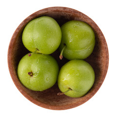 heap of green  cherry-plum in wooden cup isolated on white background