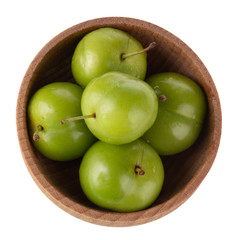 heap of green  cherry-plum in wooden cup isolated on white background