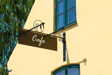 Cafe signboard on the background of the yellow wall. Close-up. Exterior. Decor.