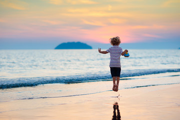 Child playing on ocean beach. Kid at sunset sea.