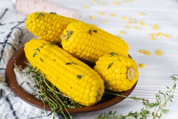 Close up boiled sweet corn cobs with salt, butter and thyme