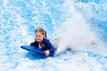 Little girl surfing in beach wave simulator