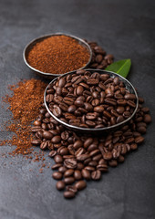 Fresh raw organic coffee beans with ground powder and coffee trea leaf on black background.