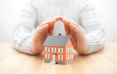 Small orange house covered by hands 