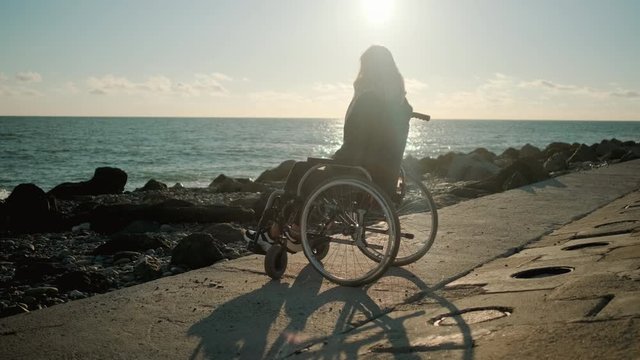 Handicapped woman in wheelchair staring at the sea