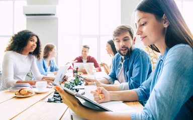 Group of young modern team in smart casual wear are discussing something while working in the creative office. Start up. Coworking space. Business ideas