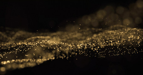 Gold glitter light particles splash wave, bokeh effect on black background. Shining gold sparks, shimmering sparkles glow in wave motion © Ron Dale