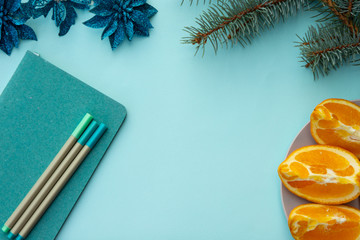 Blank notebook on bleached coral background with Christmas decorations and piece of oranges. 2020 New Year concept copyspace top horizontal view. Planning concept, flatlay style.