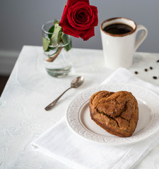 heart shaped cake, romantic breakfast, coffee and coffee beans on a light backdrop, red rose