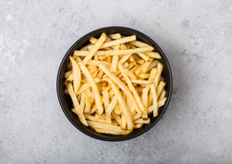 Salt and vinegar potato sticks in white bowl, classic snack on light kitchen table background.