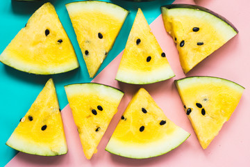 cut off triangular slices of ripe yellow watermelon on blue-pink background