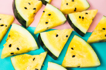 cut off triangular slices of ripe yellow watermelon on blue-pink background
