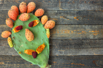 Funny smiling face created of fresh ripe exotic fruit prickly pear and lychee. Opuntia cactus with large flat pads and red thorny edible delicious fruits. Prickly pears fruit on wood. Enjoy meal