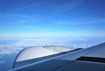 Blue sky with clouds and the part of the airplane as looking through the window on the flight from Atlanta USA to Korea.