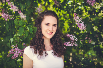 Naklejka premium Cheerful young woman in a white t-shirt under the blooming trees.
