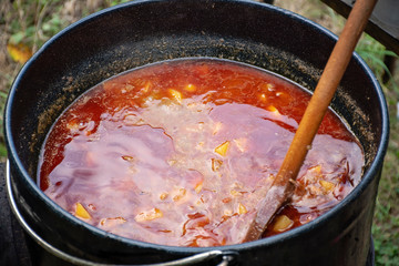 Cooking delicious kettle goulash with in a large cauldron outdoors