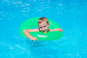 Happy kid boy having fun in an swimming pool. Active happy healthy preschool child learning to swim. With safe floaties or swimmies.