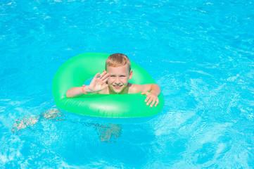 Fototapeta na wymiar Cute kid swimming in a pool with clear water
