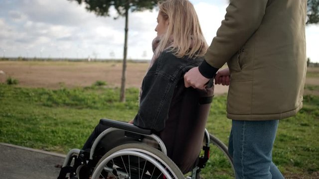 Man walking with handicapped girl in wheelchair