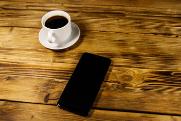 Cup of coffee and smartphone on a wooden table