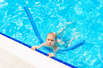 Boy at swimming pool class learning to swim.