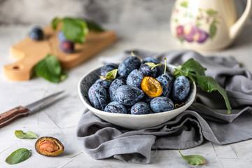 Dark blue plum in a plate on a white table.