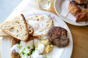 American breakfast with sausage patty, sourdough bread toast, fried egg, and potatoes, top view