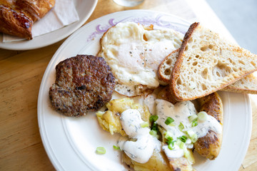 American breakfast with sausage patty, sourdough bread toast, fried egg, and potatoes, top view
