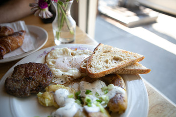 American breakfast with sausage patty, sourdough bread toast, fried egg, and potatoes, top view