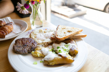 American breakfast with sausage patty, sourdough bread toast, fried egg, and potatoes, top view