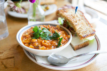 Close up of minestrone soup with california club sandwich on cafe table
