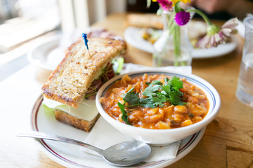 Close up of minestrone soup with california club sandwich on cafe table