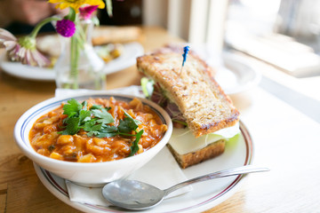 Close up of minestrone soup with california club sandwich on cafe table