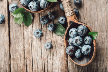 Blueberries in wooden spoon on old wood table. Healthy eating and nutrition concept.
