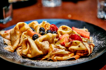 Pancakes with berries (blueberries and strawberries) are poured with caramel sauce.