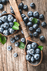 Blueberries in wooden spoon on old wood table. Healthy eating and nutrition concept.