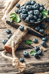 Freshly picked blueberries in bowl on wooden background. Healthy eating and nutrition.