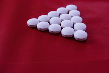 White round medicinal pills lie on a red background in the form of a pyramid