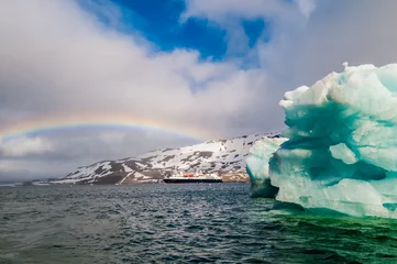 Fotobehang Cruise ship under a rainbow cruising past an iceberg in Hornsund Svalbard Norway within the arctic circle. © Don Landwehrle