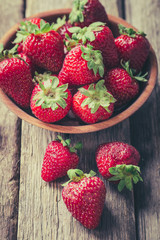 Freshly picked Strawberry in wooden bowl on wooden background. Healthy eating and nutrition.