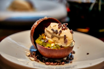 Ice cream with fruit in the chocolate sphere