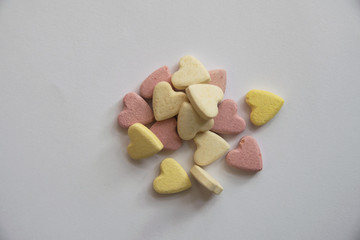 .pink and yellow Vitamins in the shape of a heart lie on a white background in a small heap leaving an empty space
