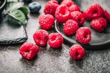 Freshly picked raspberries in bowl on old metal background. Healthy eating and nutrition.