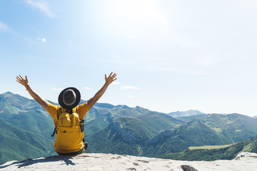 Young Man Hands Up Sitting on Top of a Mountain .