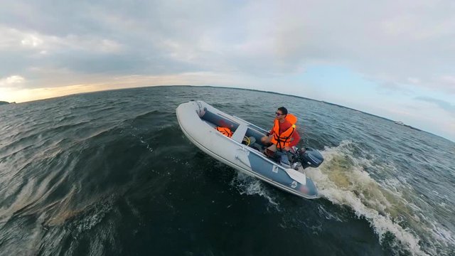 A man drives on inflatable boat on waves.