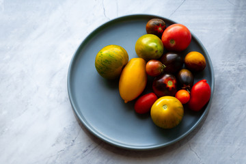 Tomatoes of different varieties in a bowl. Multi-colored washed crop on a plate. Cherry collected from the garden