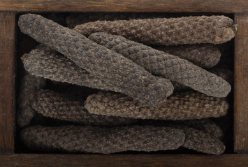 heap of pippali (long pepper) in wooden box. top view
