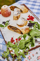 Apple strudel and apple on a board sprinkled with powdered sugar