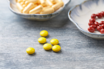Vitamin C, Beta-Carotene tablets and Coenzyme Q10 capsules. Antioxidants. Concept for a healthy dietary supplementation. Bright wooden background. Close up. Copy space.  