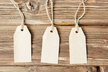 Paper hang on clothesline Three paper empty tags with rope on wooden background.
